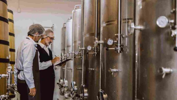Two people performing quality control in a beverage production area.