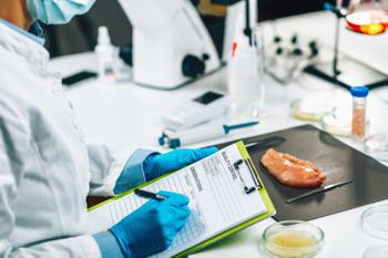 Food safety and quality inspector filling out a form in a laboratory with a poultry sample in background